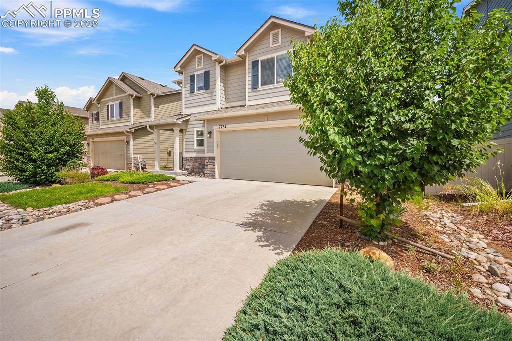 Image 33 of 50: View of front of property featuring an attached garage, driveway, and stone