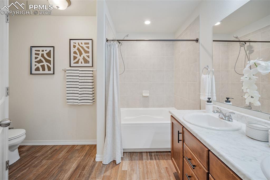Image 4 of 50: Full bath featuring wood finished floors, vanity, shower / bathtub combinat