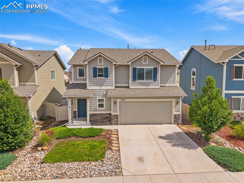 Image 42 of 50: View of front of house featuring driveway, an attached garage, stone siding