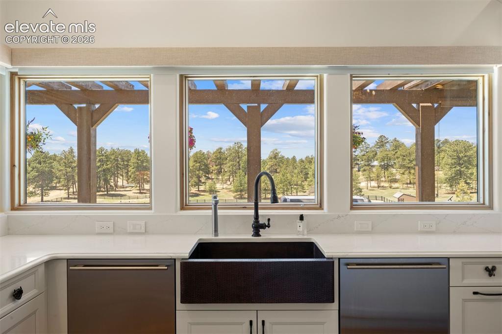 Image 15 of 46: Wrap-around windows in the kitchen overlook the pergola, patio, pastures, a