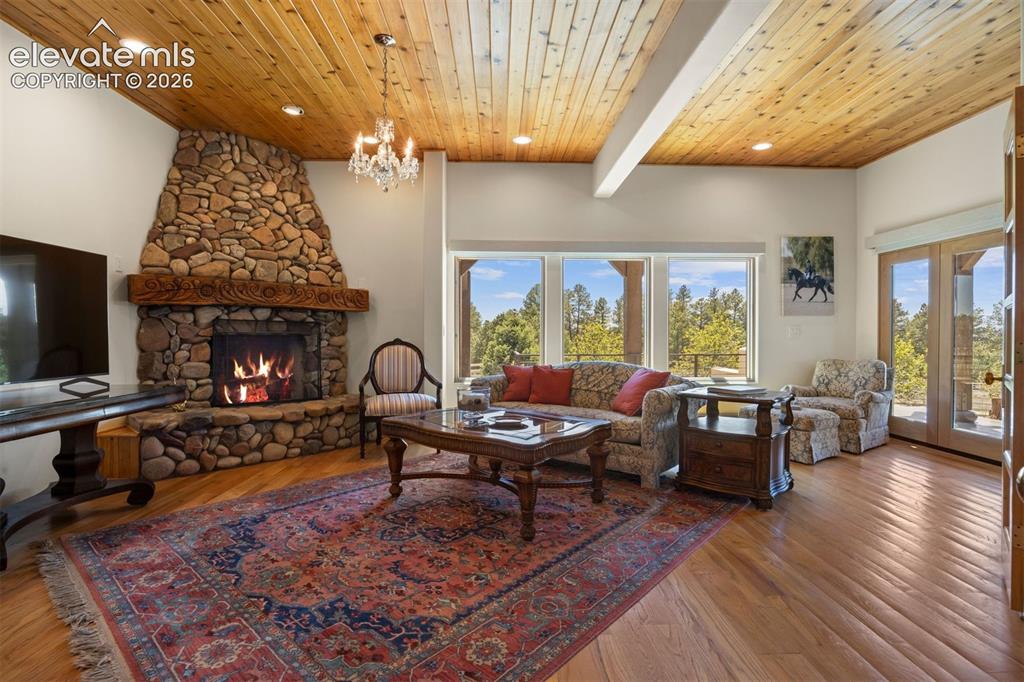 Image 18 of 46: The den features a Dramatic floor-to-ceiling stacked river stone wood-burni
