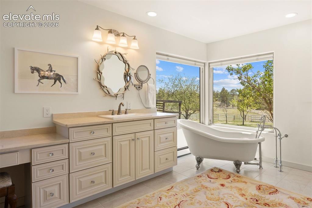 Image 23 of 46: Primary bathroom one with claw-foot soaking tub nestled by two large corner