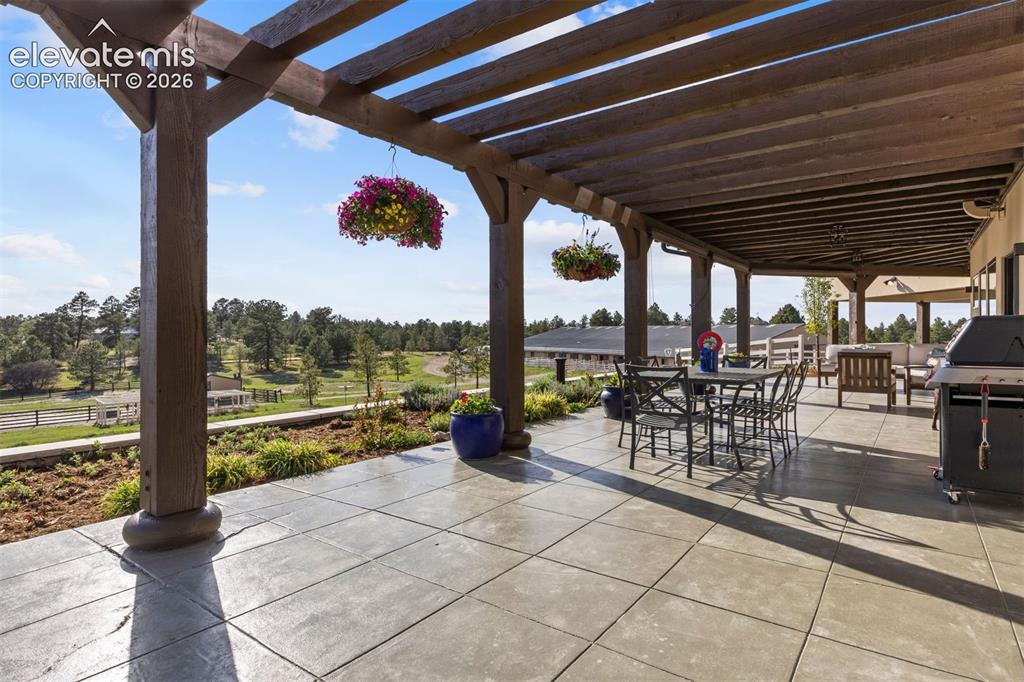 Image 27 of 46: Expansive patio, partially covered by two striking pergolas, wraps the full