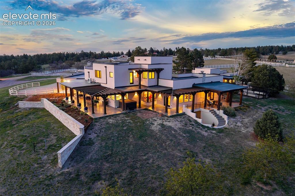 Image 29 of 46: Rear overview showing the expansive patio and architectural detail of the h