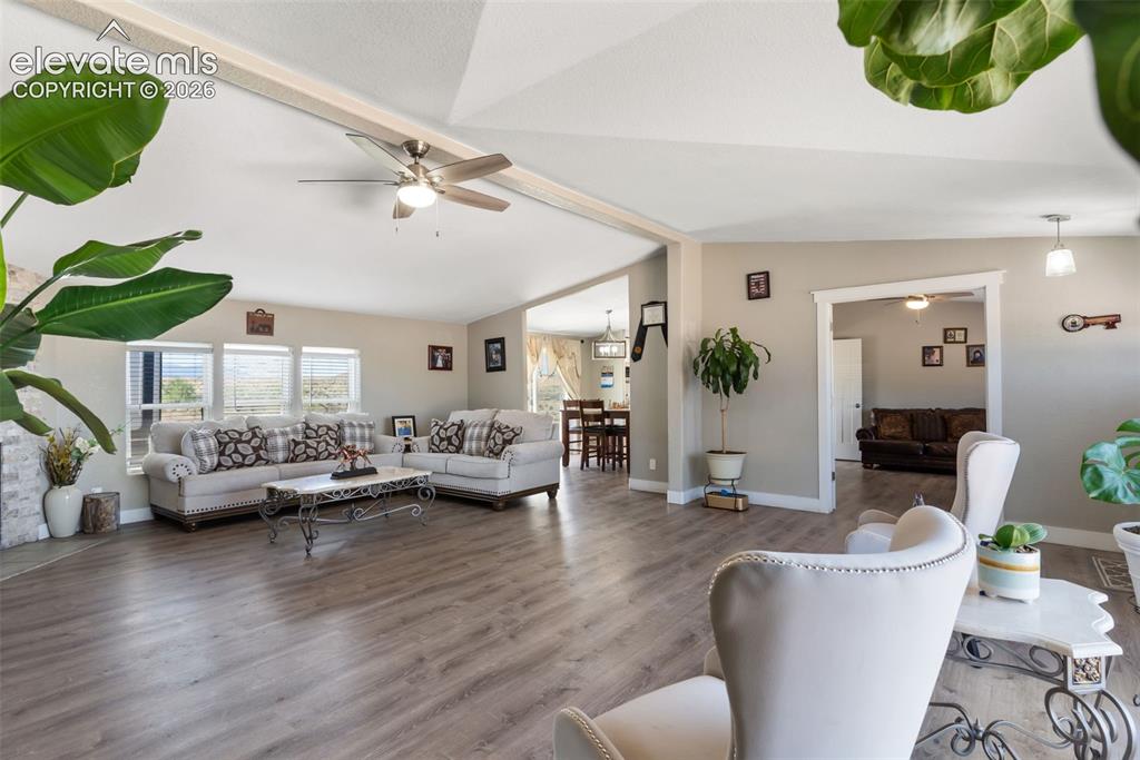 Image 10 of 34: Spacious living area featuring wood-finish flooring, vaulted ceilings, and 