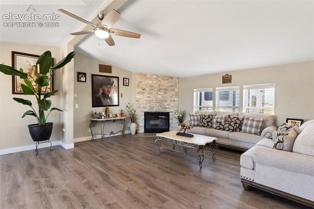 Image 11 of 34: Living space featuring wood-finish flooring, a corner fireplace with a ston
