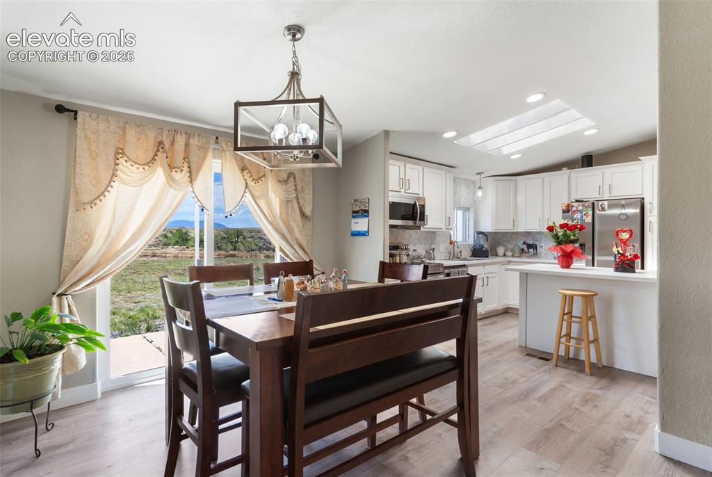 Image 13 of 34: Open-concept dining area with wood-finish flooring, featuring a contemporar