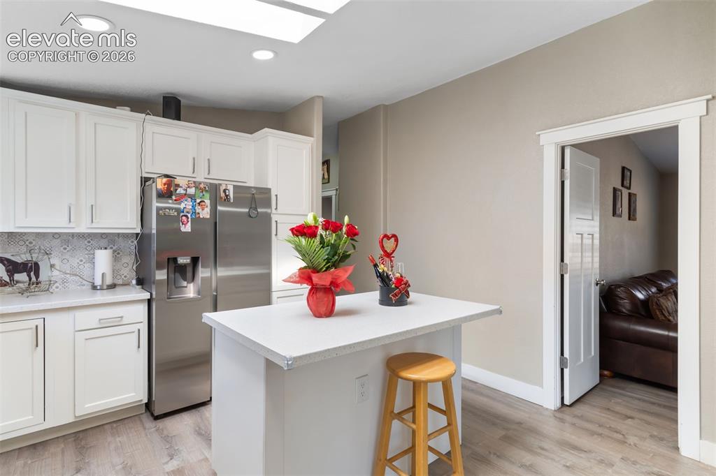 Image 14 of 34: Kitchen featuring white cabinetry with brushed nickel hardware, a central i