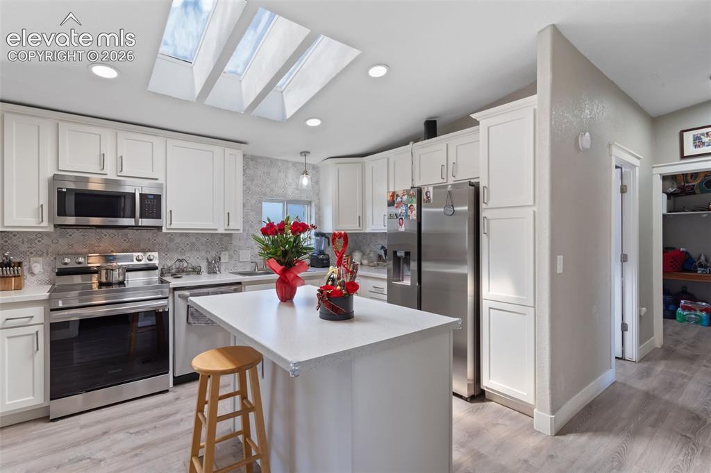 Image 15 of 34: Kitchen featuring white cabinetry, stainless steel appliances, and a centra