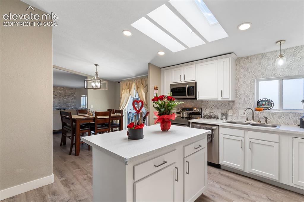 Image 16 of 34: Kitchen featuring white cabinetry, a central island, light countertops, woo
