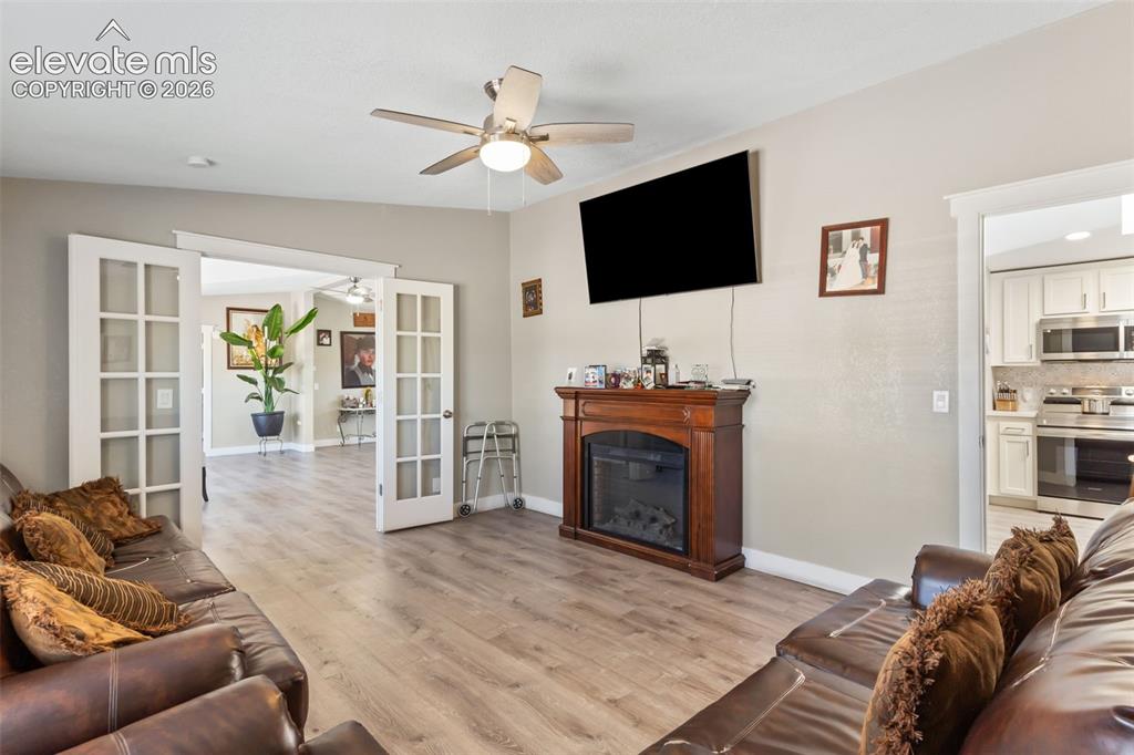 Image 17 of 34: Living area featuring wood-finish flooring, a ceiling fan, and a built-in e