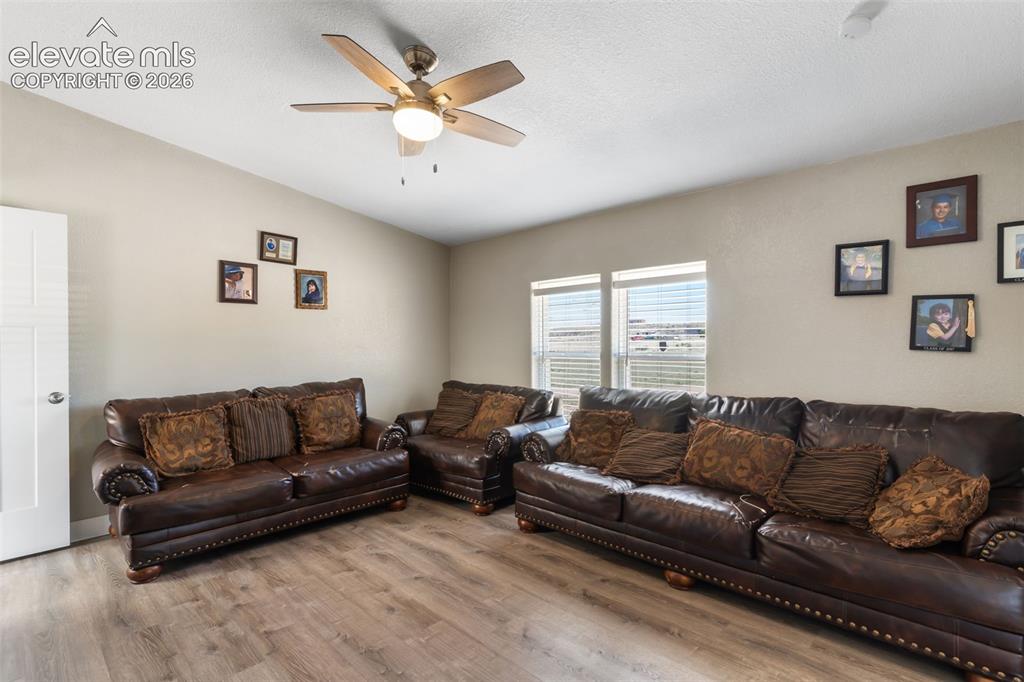 Image 18 of 34: Living area featuring wood-finish flooring, two windows with horizontal bli