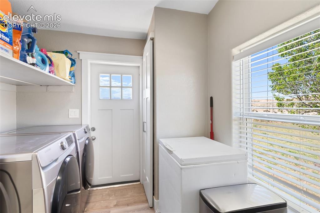 Image 19 of 34: Utility room featuring wood-finish flooring, a white paneled door with glas