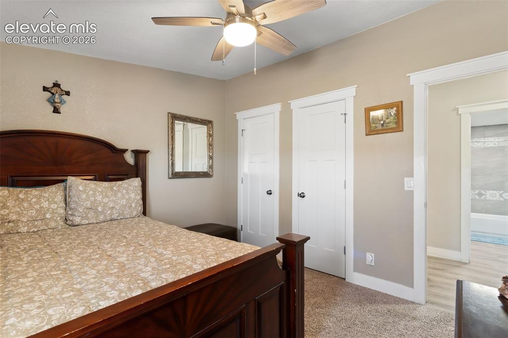 Image 27 of 34: Carpeted room featuring a ceiling fan with integrated lighting, two white p