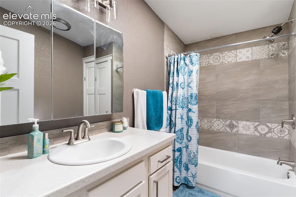 Image 28 of 34: Bathroom featuring a white vanity with an undermount sink, brushed nickel f