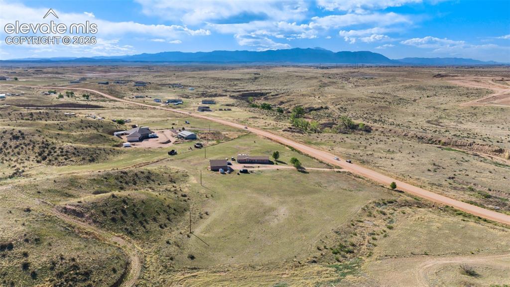 Image 33 of 34: Expansive rural landscape with distant mountains, featuring a cluster of st