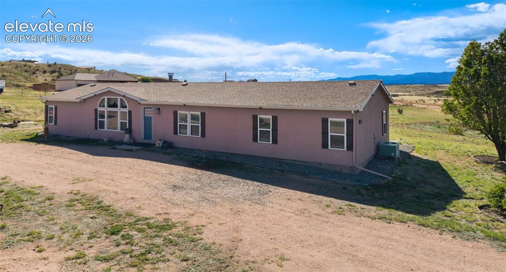 Image 4 of 34: Single-story stucco residence featuring a prominent arched window, dark con