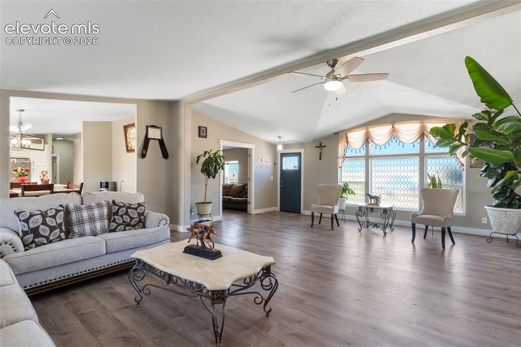 Image 9 of 34: Spacious living area featuring wood-finish flooring and a vaulted ceiling w