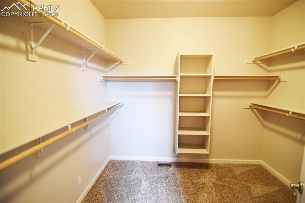 Image 19 of 29: Spacious walkin closet with lots of rods and built-in shelves.