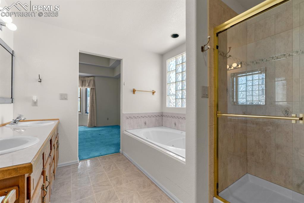 Image 15 of 38: Full bathroom with double vanity, a shower stall, and a bath
