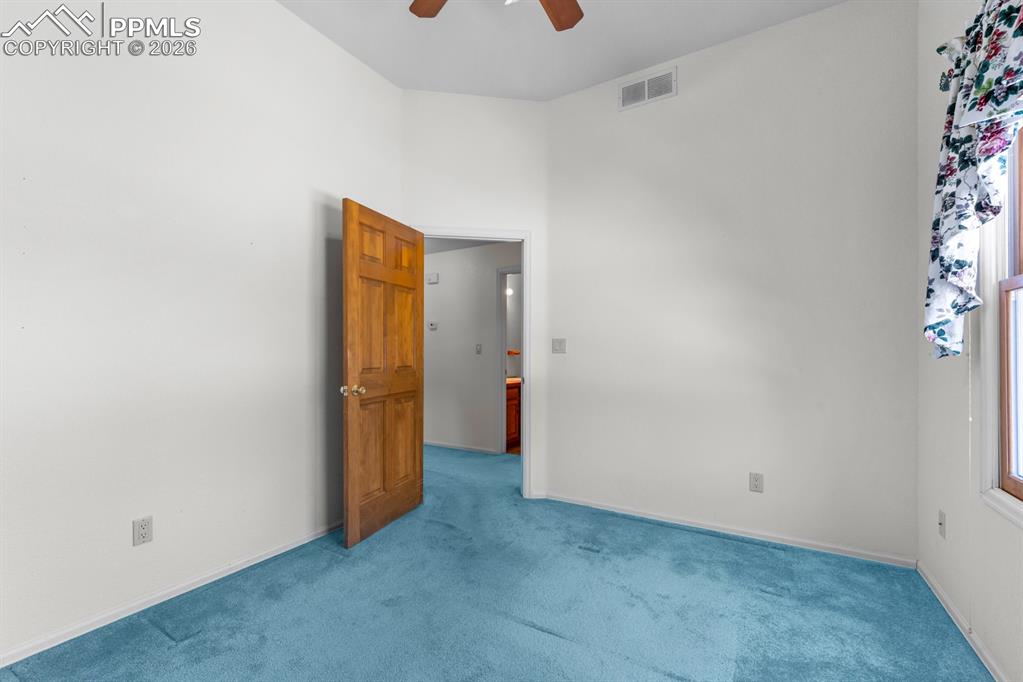 Image 17 of 38: Carpeted empty room with ceiling fan and a high ceiling