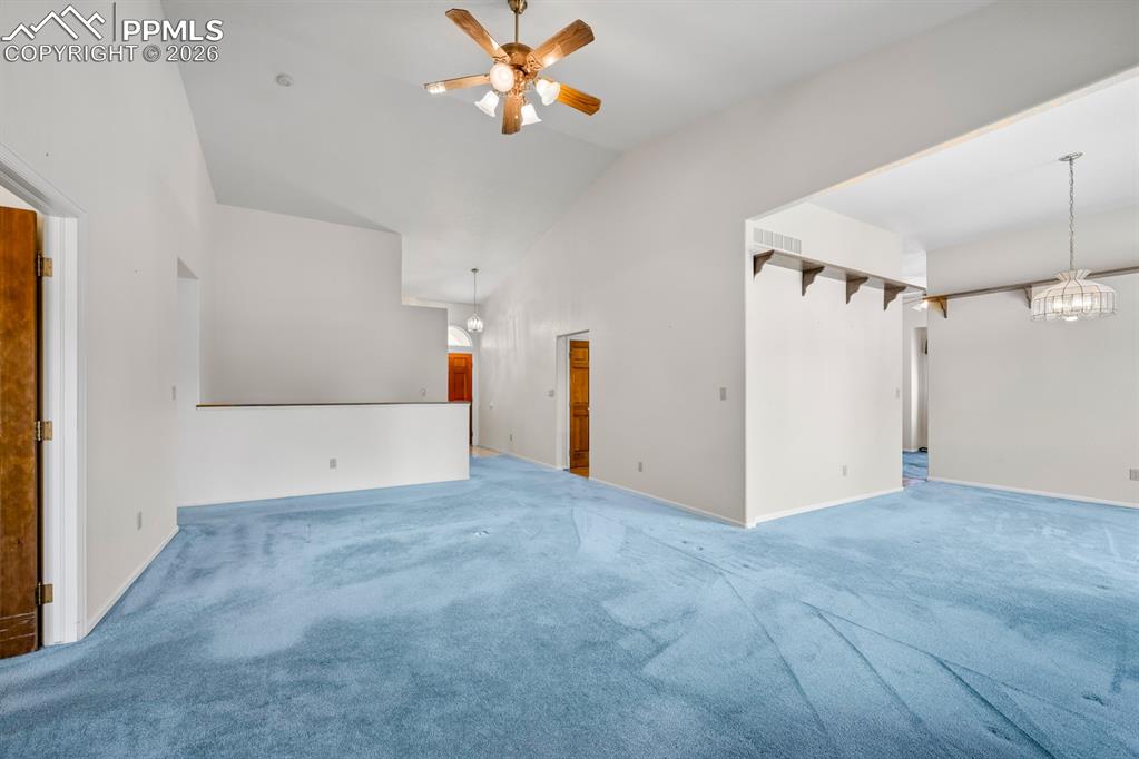Image 5 of 38: Unfurnished living room featuring carpet, a ceiling fan, a chandelier, and 