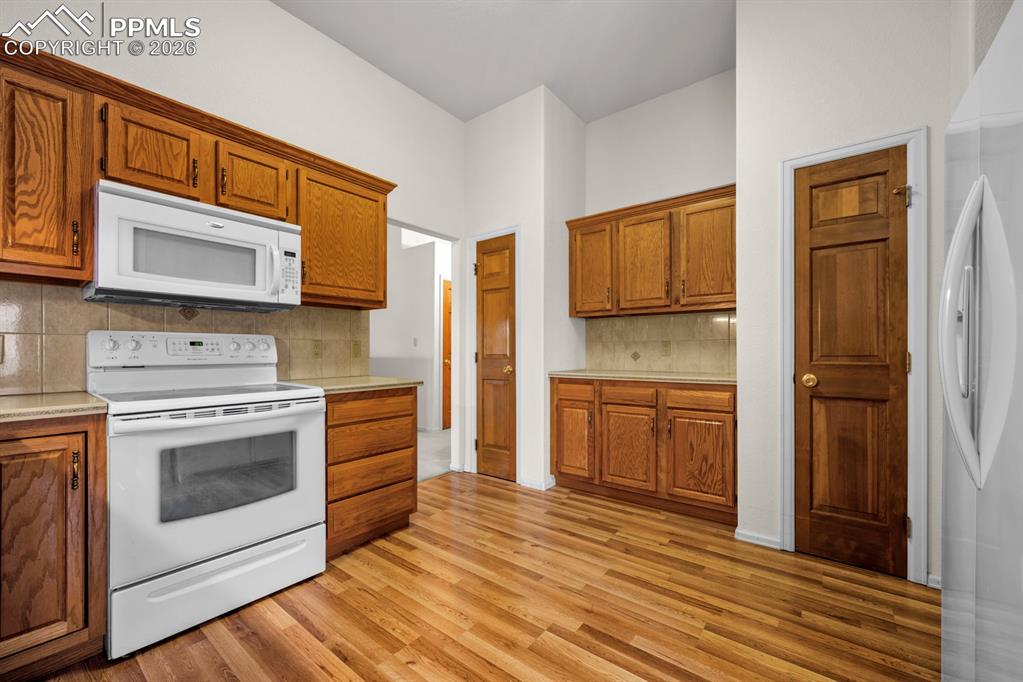 Image 8 of 38: Kitchen featuring white appliances, light countertops, and wood finish cabi