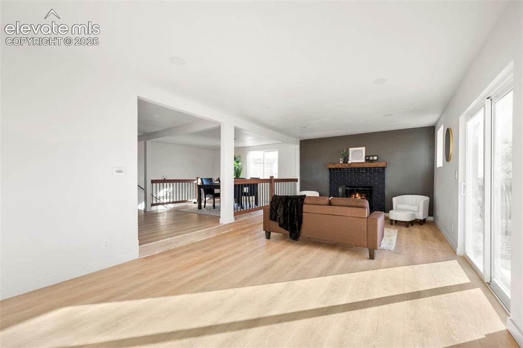 Image 12 of 49: Living area featuring light wood-finish flooring, a dark accent wall with a