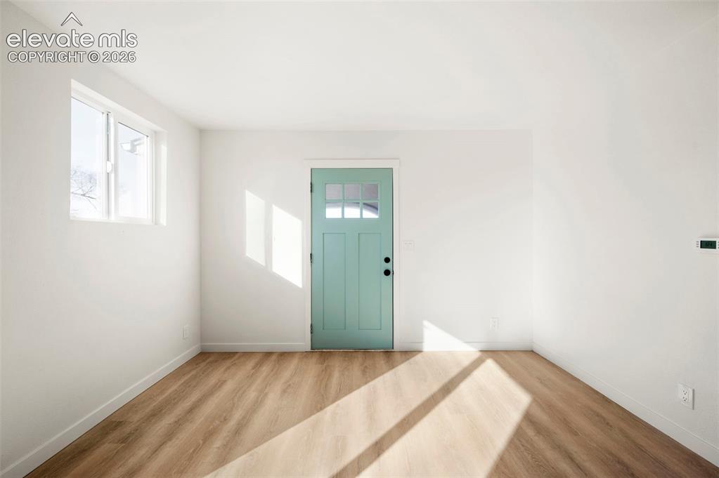 Image 16 of 49: Light-filled room featuring a teal multi-pane door, wood-finish flooring, w