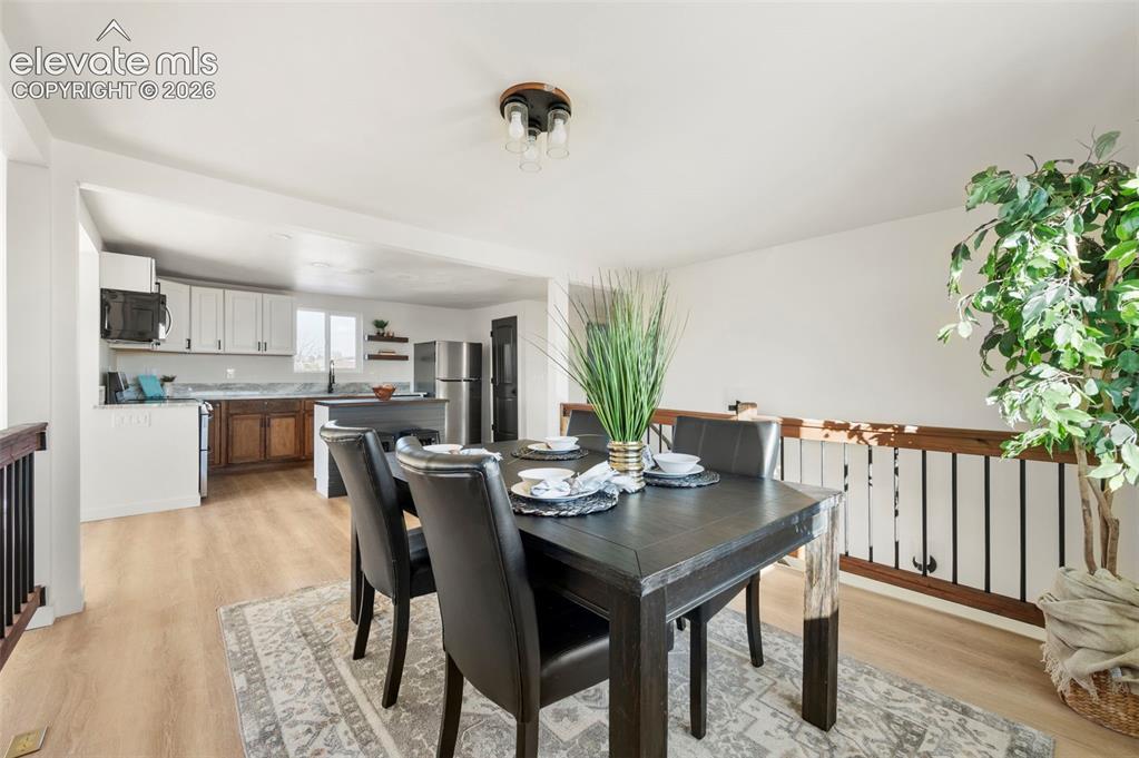 Image 17 of 49: Open-concept living area featuring light wood-finish flooring, a kitchen wi