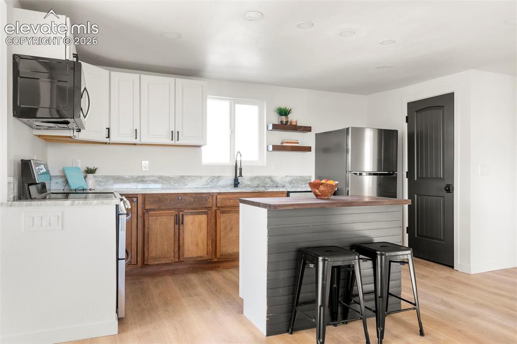 Image 19 of 49: Modern kitchen featuring a two-toned cabinetry scheme, light wood-finish fl