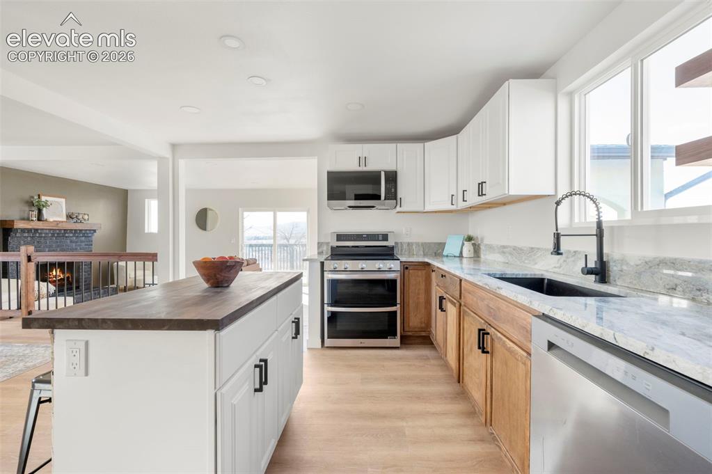 Image 22 of 49: Modern kitchen featuring a large central island with a wood-finish countert