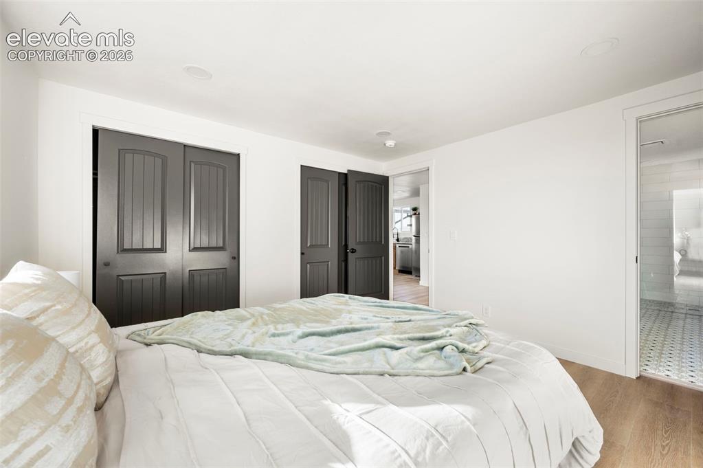 Image 26 of 49: Bright interior featuring wood-finish flooring and two dark paneled bifold 