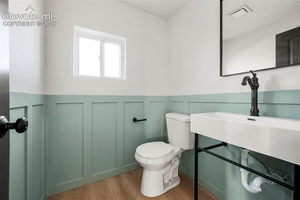 Image 32 of 49: Modern powder room featuring wainscoting, a rectangular vessel sink with ma