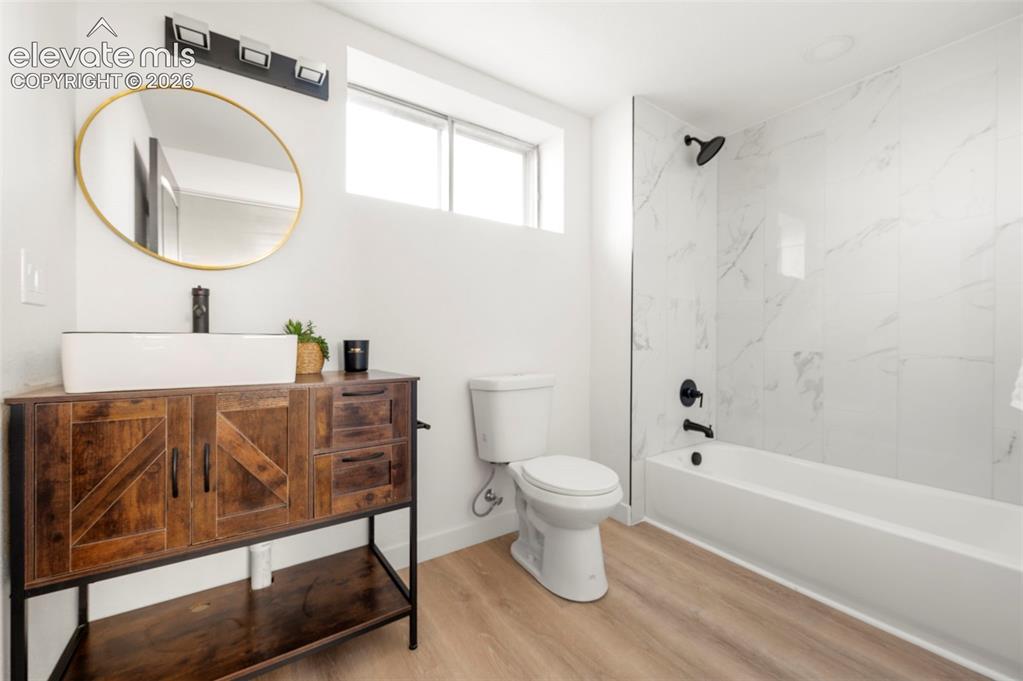 Image 38 of 49: Modern bathroom featuring a wood-finish vanity with a rectangular vessel si