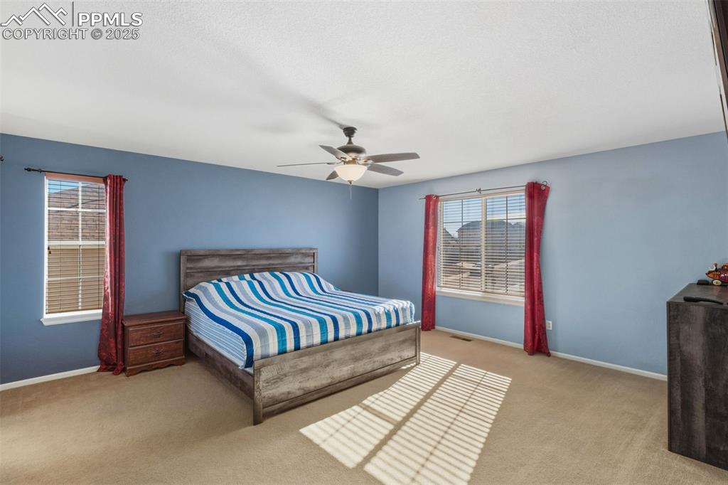 Image 14 of 33: Bedroom with ceiling fan and light carpet