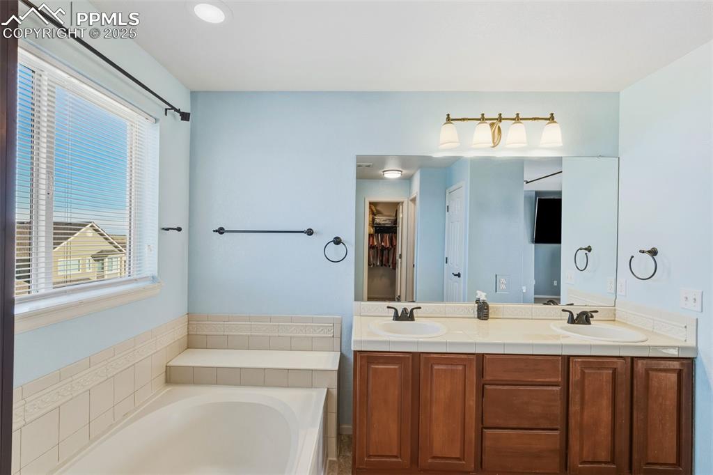 Image 16 of 33: Full bath with double vanity and a bath