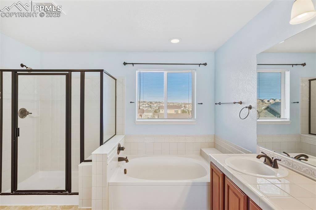 Image 17 of 33: Full bathroom featuring a garden tub, vanity, and a shower stall