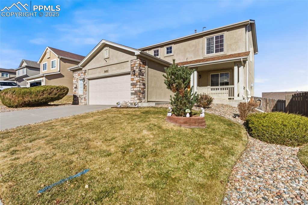 Image 2 of 33: Traditional home with stucco siding, driveway, a porch, stone siding, and a