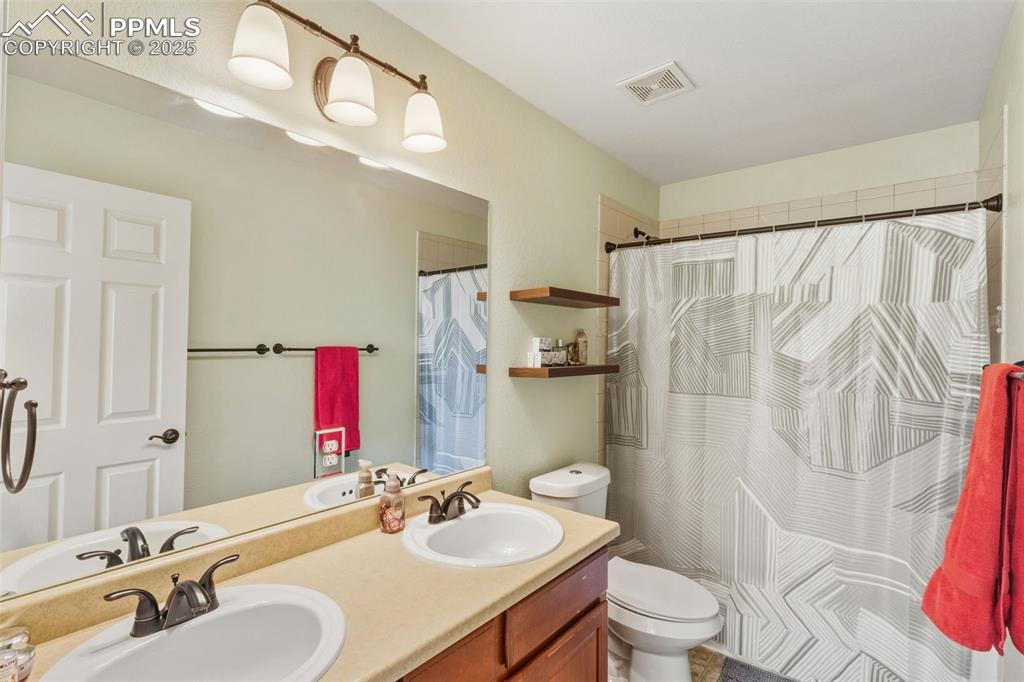 Image 21 of 33: Full bath with double vanity and curtained shower