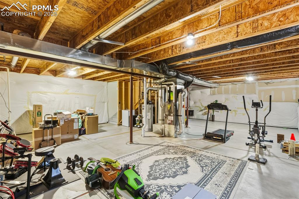 Image 23 of 33: Unfinished below grade area with water heater and washer / dryer