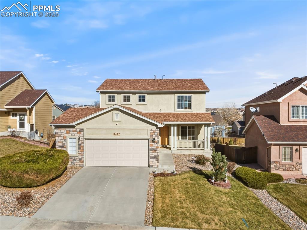 Image 25 of 33: Traditional home with stucco siding, a porch, concrete driveway, stone sidi