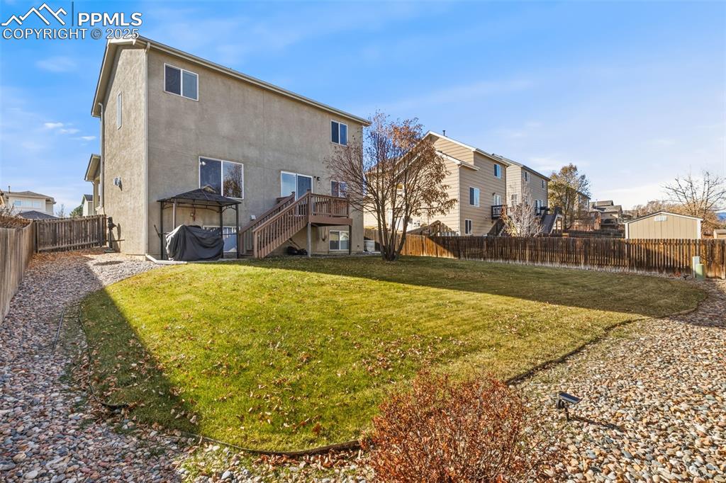 Image 28 of 33: Back of property with a fenced backyard, a deck, stucco siding, and stairwa