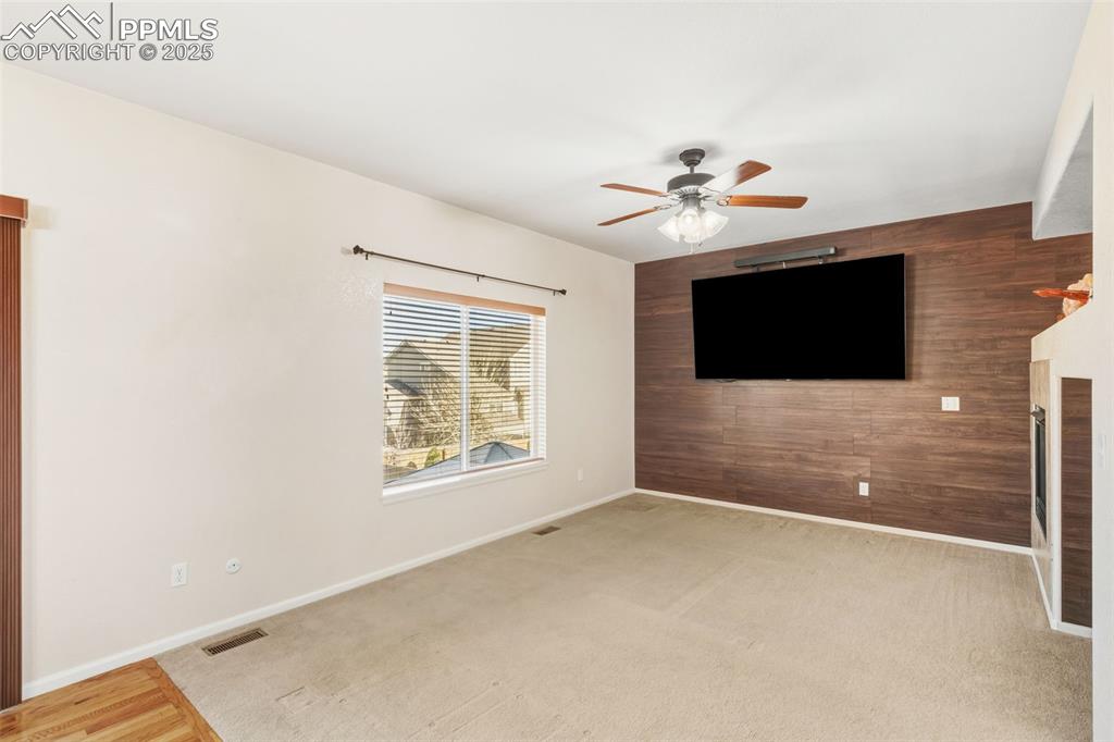 Image 5 of 33: Unfurnished living room featuring wood walls, an accent wall, light carpet,