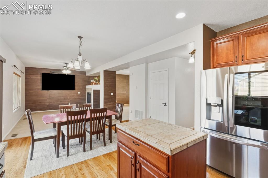 Image 8 of 33: Kitchen featuring an accent wall, stainless steel fridge, brown cabinetry,