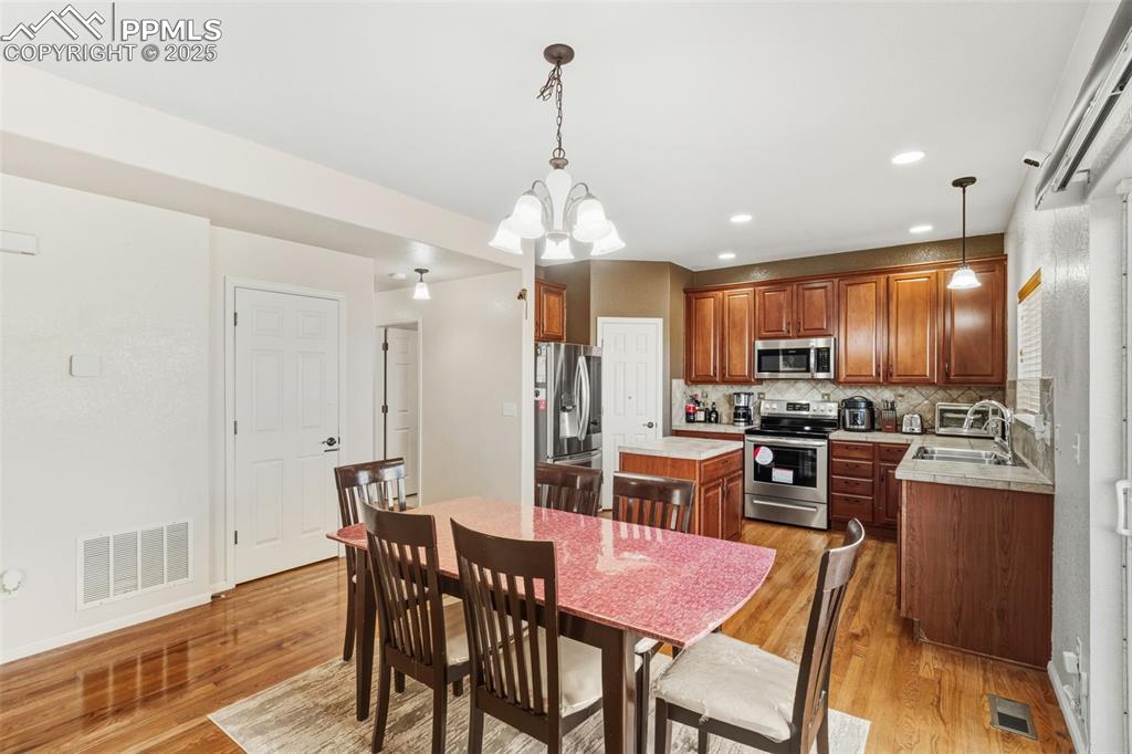 Image 9 of 33: Kitchen with decorative light fixtures, light countertops, stainless steel