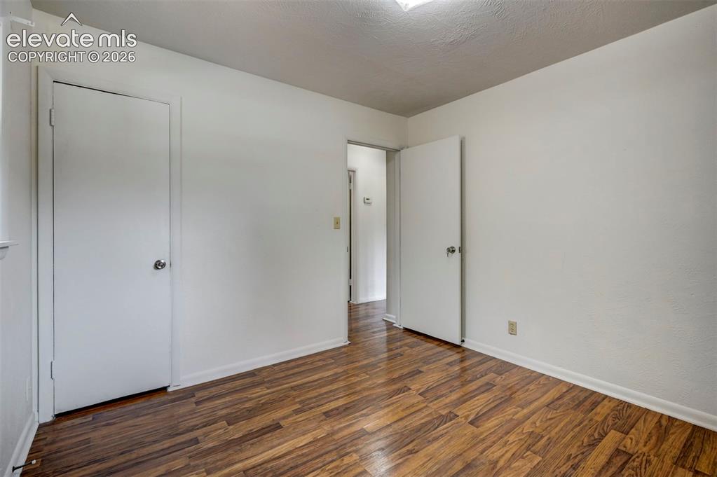 Image 28 of 40: Room featuring wood-finish flooring, white walls, and a ceiling-mounted lig