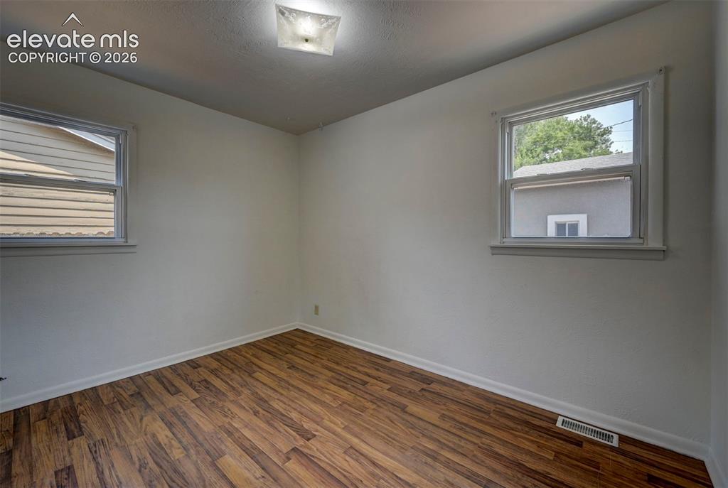 Image 29 of 40: Empty room with wood-finish flooring, light-toned walls, and two single-hun