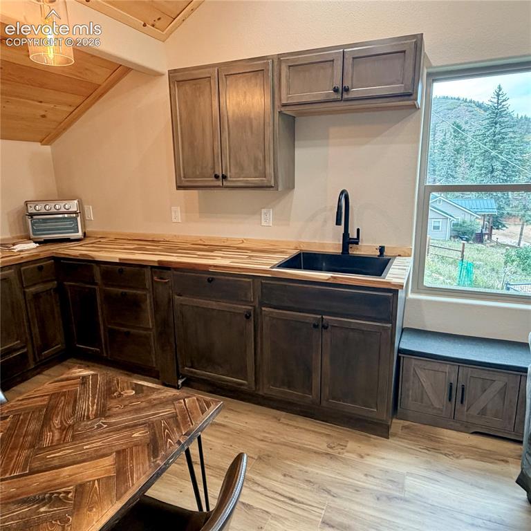 Image 13 of 45: Wood-finish flooring with dark wood cabinetry and light wood countertops