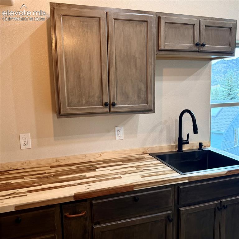 Image 9 of 45: Wood-finish butcher block countertop with an undermount sink and matte blac